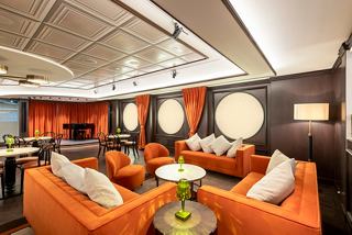 A stylish lounge area with orange sofas and elegant decor, perfect for relaxation and socialising | MSC Cruises
