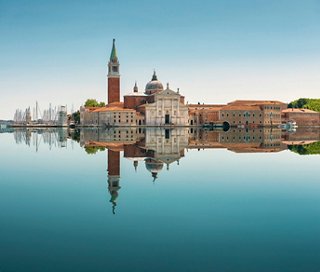 Die ruhige Reflexion der ikonischen Insel San Giorgio Maggiore in Venedig und ihres Turms auf ruhigem Wasser | MSC Cruises