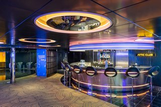 Un bar elegante en el Attic Club a bordo del MSC Virtuosa, con iluminación vibrante y un ambiente acogedor | MSC Cruceros