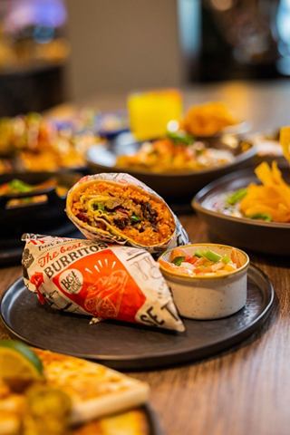 Una vibrante selección de platos que incluyen tacos y burritos dispuestos en platos en un restaurante | MSC Cruceros