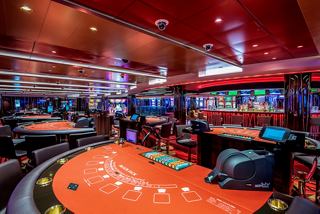 A vibrant view of the Red Gem Casino on MSC Virtuosa, featuring gaming tables and slot machines | MSC Cruises