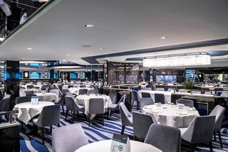 Elegant dining area with neatly arranged tables and blue accents, inviting guests to enjoy a delightful meal together | MSC Cruises