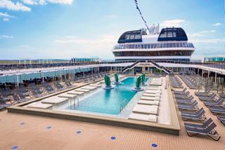 A serene pool area on MSC Virtuosa, featuring sun loungers and a bright blue sky above | MSC Cruises