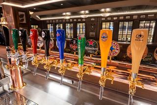 A vibrant selection of beer taps in a pub setting on the MSC Virtuosa, inviting guests to enjoy refreshing drinks | MSC Cruises