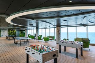 A modern lounge area with large windows, greenery, and seating for relaxation aboard the MSC Seashore | MSC Cruises