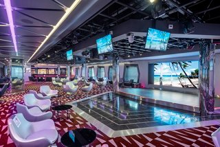 A vibrant bar area with screens and a stage, inviting guests to enjoy entertainment and socialising | MSC Cruises