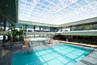 A spacious indoor pool area featuring a sliding roof and tropical bar, inviting relaxation and enjoyment | MSC Cruises