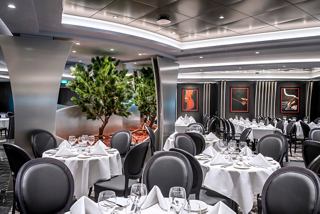 Elegant dining area featuring tables set for guests, adorned with plants and artwork, inviting a warm atmosphere | MSC Cruises