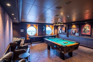 A stylish sports bar with a pool table, portholes, and inviting seating for relaxation and entertainment | MSC Cruises