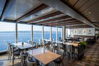 A bright dining area with tables arranged by large windows overlooking the sea | MSC Cruises