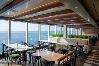 A spacious restaurant with large windows offering sea views, featuring tables set for dining | MSC Cruises