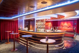 A stylish bar area with a vibrant atmosphere, featuring a curved counter and tables for relaxed socialising | MSC Cruises
