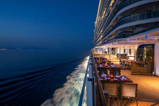 A beautifully lit outdoor dining area on the MSC Seashore, overlooking the serene sea at night | MSC Cruises