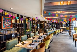 A vibrant dining area featuring tables and chairs in Hola! Tacos & Cantina aboard MSC Seashore | MSC Cruises