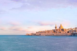 Un sereno amanecer sobre el puerto de Marsamxett con la Basílica de Nuestra Señora del Monte Carmelo a lo lejos | MSC Cruceros