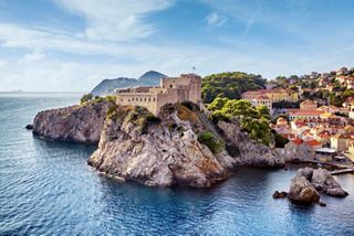 Eine atemberaubende Küstenansicht von Dubrovnik mit den alten Mauern und Fort Lovrijenac am ruhigen Meer | MSC Cruises