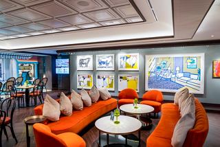 A vibrant lounge area with orange seating and an artistic wall, perfect for relaxation and socialising | MSC Cruises
