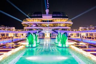 The vibrant pool area of MSC Virtuosa illuminated at night, showcasing a lively atmosphere and inviting design | MSC Cruises