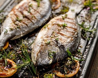 Pescado a la parrilla adornado con limón y romero, mostrando un delicioso plato de mariscos de La Pescaderia | MSC Cruceros