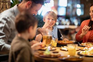 Una familia disfruta de una comida junta en un restaurante, compartiendo risas y deliciosa comida | MSC Cruceros