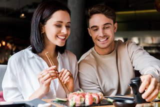 A couple enjoying sushi together at a restaurant, sharing a delightful dining experience | MSC Cruises
