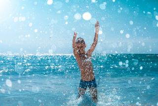 A child joyfully plays in the water, embracing the sunny day with happiness | MSC Cruises