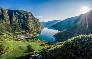 A breathtaking aerial view of Flaam, showcasing its fjord, mountains, and sunlight reflecting on the water | MSC Cruises