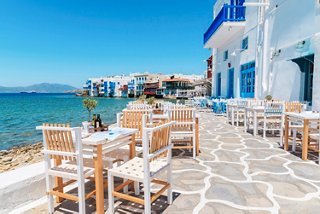 A charming seaside restaurant with tables and chairs overlooking the serene sea in Mykonos, Greece | MSC Cruises