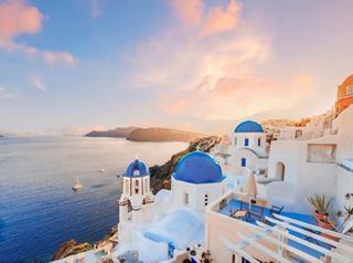 Un tramonto mozzafiato sul mare con iconici edifici a cupola blu a Santorini, Grecia | MSC Crociere