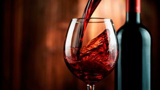 A glass of red wine with a bottle in the background, capturing a moment of relaxation and enjoyment | MSC Cruises