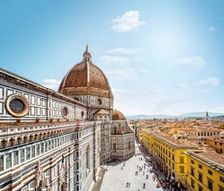 A panoramic view of the Florence Duomo, showcasing its iconic dome and surrounding architecture under a clear sky | MSC Cruises