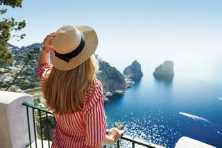 A woman admires the stunning Capri panorama overlooking the sea and iconic Faraglioni rocks | MSC Croisières