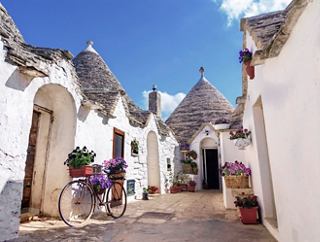 Charming traditional trulli houses with flowers, inviting exploration in the picturesque town of Alberobello, Italy | MSC Cruises