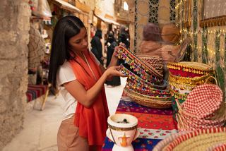 Une femme choisit joyeusement un souvenir tout en explorant la culture locale vibrante à Yanbu, Arabie Saoudite | MSC Cruises