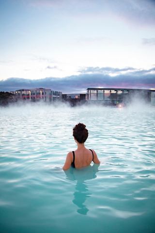 A woman relaxes in the warm mineral waters of the Blue Lagoon, enjoying the serene landscape of Reykjavik | MSC Cruises
