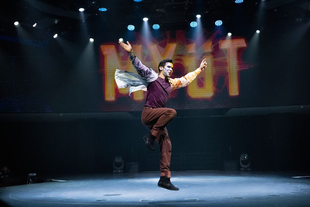 A performer captivates the audience with an energetic dance routine under vibrant stage lights | MSC Cruises