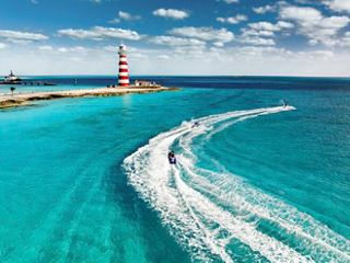 Aerial view of a waverunner creating waves in the turquoise waters near a lighthouse at Ocean Cay | MSC Cruises