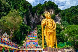 Une majestueuse statue dorée aux grottes de Batu entourée d'une végétation luxuriante et d'escaliers de temple vibrants | MSC Cruises