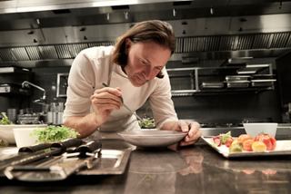 Un chef prepara cuidadosamente un plato en una cocina moderna a bordo del MSC World Europa | MSC Cruceros