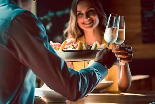 Una pareja disfruta de champán juntos en La Pescaderia, creando recuerdos duraderos en un ambiente cálido | MSC Cruceros