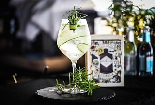 A refreshing gin and tonic cocktail garnished with rosemary and fresh cucumber sits elegantly on a plate | MSC Cruises