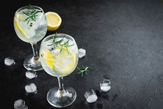 Refreshing gin and tonic cocktails with lemon and rosemary garnishes served on a dark surface | MSC Cruises