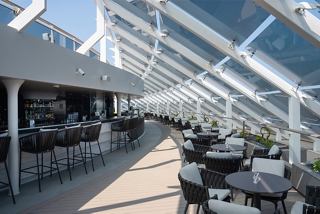 Stilvolles Esszimmer mit Außensitzplätzen und einer Bar im MSC Yacht Club auf der MSC World Europa | MSC Cruises