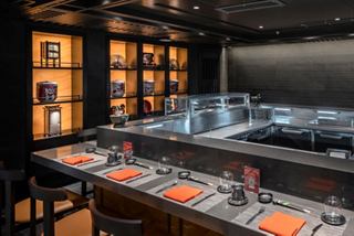 Un elegante comedor con el Kaito Sushi Bar, asientos y estantes iluminados | MSC Cruceros