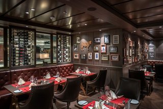 Elegant dining setup in a speciality restaurant featuring tables, chairs, and wine bottles | MSC Cruises