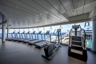 Ein heller und moderner Fitnessraum mit verschiedenen Fitnessgeräten und Panoramablick auf den Ozean | MSC Cruises