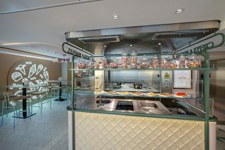 A welcoming bar area featuring a glass display of sweets and waffles, inviting guests to indulge in delightful treats | MSC Cruises