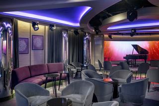A vibrant lounge with a piano and comfortable seating, perfect for enjoying live music and socialising | MSC Cruises
