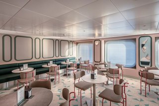 A stylish lounge featuring tables and chairs, with a view of the sea through large portholes | MSC Cruises