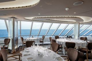 A spacious MSC Yacht Club restaurant features panoramic views of the sea through large glass walls | MSC Cruises